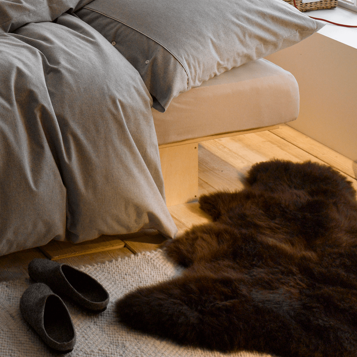 Schaffell für Hunde, braun mit Naturspitze vor Bett liegend.