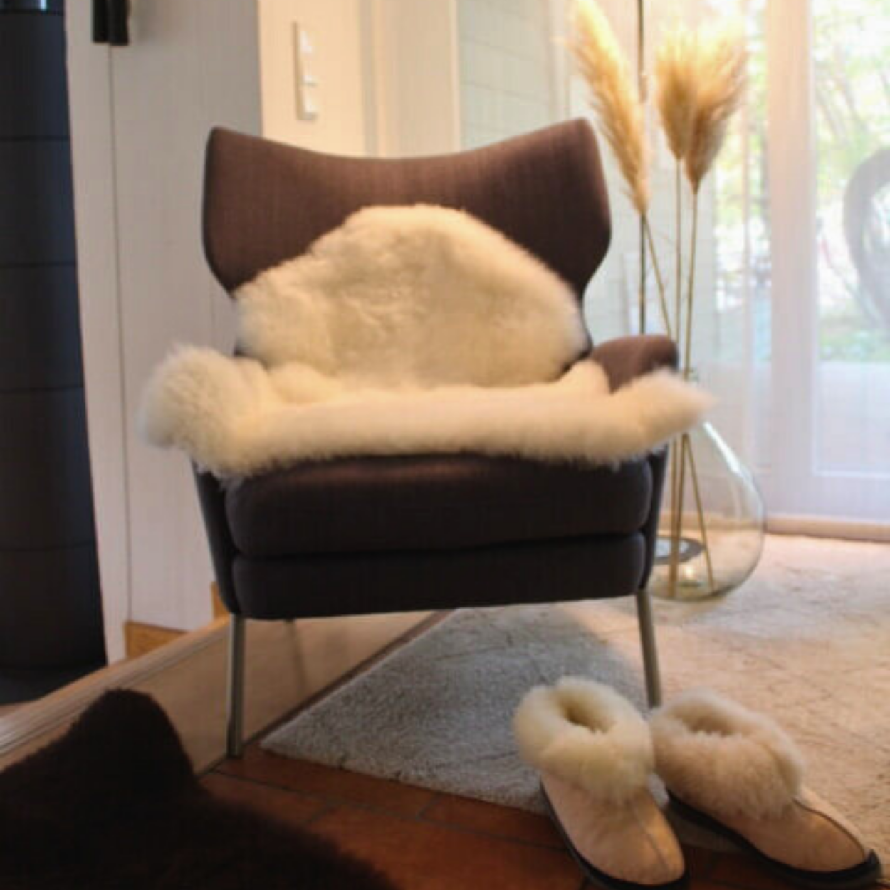 Ein kuscheliges Schaffell liegt in einem Wohnzimmer vor dem Ofen.